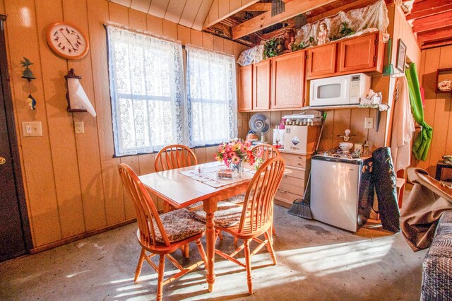 dining space with wood walls and a healthy amount of sunlight