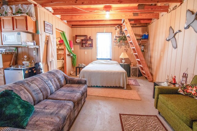 bedroom featuring beamed ceiling, concrete floors, and wood walls