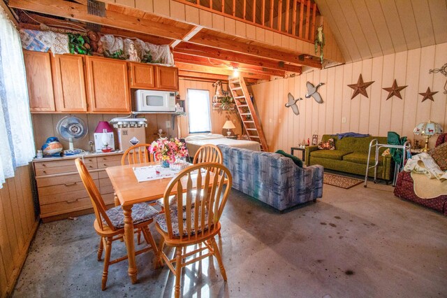 dining room featuring wooden walls and lofted ceiling