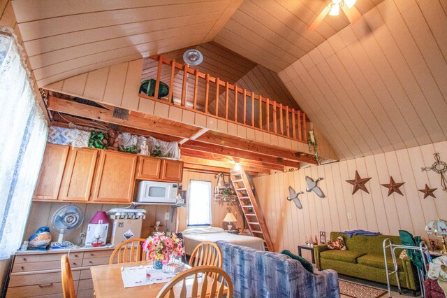 dining room with wooden walls, ceiling fan, and lofted ceiling