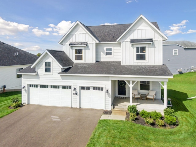 view of front of property featuring covered porch, a front lawn, board and batten siding, and a garage