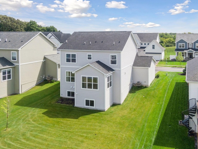 rear view of property featuring a shingled roof, a residential view, a lawn, and central AC unit