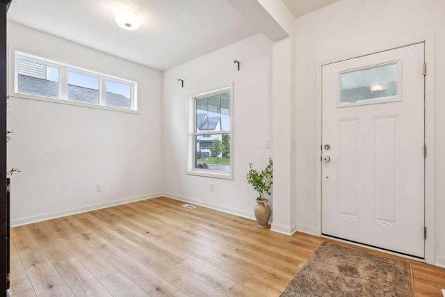 entryway featuring baseboards, visible vents, and light wood finished floors