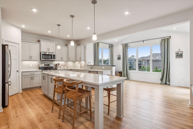 kitchen featuring light wood-style flooring, a center island, a sink, stainless steel appliances, and backsplash