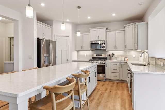 kitchen featuring stainless steel appliances, light wood-type flooring, a sink, and backsplash