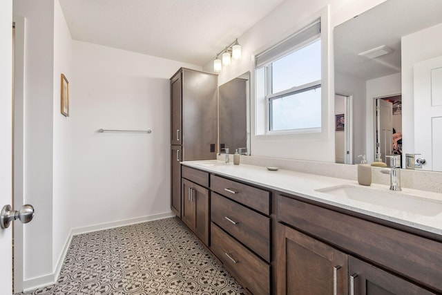 bathroom featuring tile patterned floors, a sink, baseboards, and double vanity