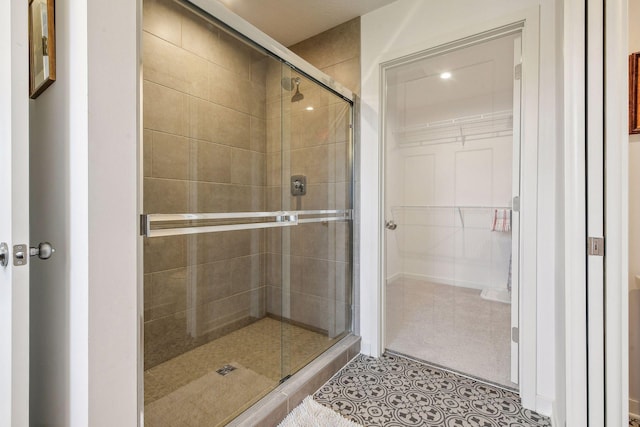 full bathroom featuring a walk in closet, tile patterned flooring, and a shower stall