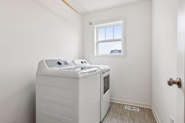 laundry room featuring laundry area, washing machine and dryer, visible vents, and baseboards