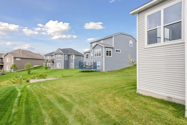 view of yard featuring a trampoline and a residential view