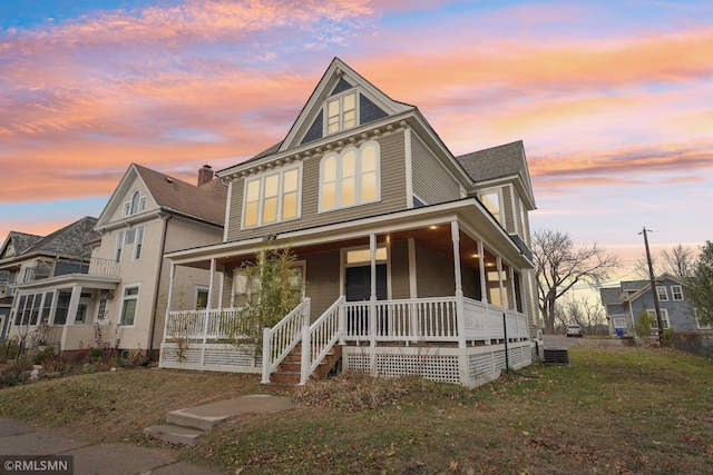 view of front of home featuring covered porch, a yard, and cooling unit