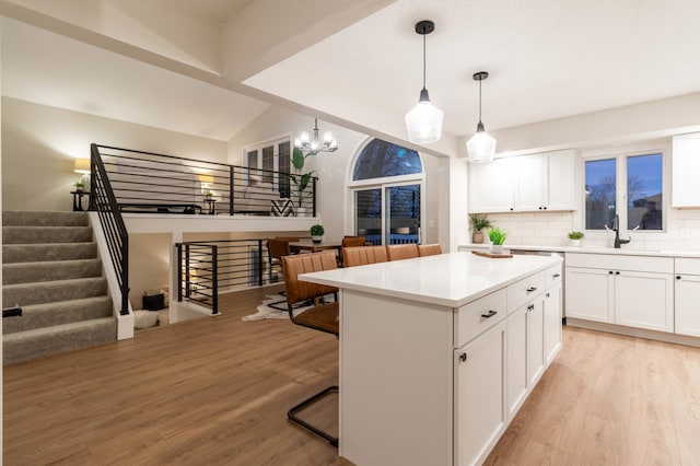 kitchen featuring a center island, hanging light fixtures, light hardwood / wood-style flooring, decorative backsplash, and white cabinets