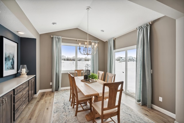 dining space featuring a chandelier, lofted ceiling, and light wood-type flooring