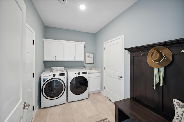 clothes washing area with cabinets, washing machine and dryer, light hardwood / wood-style flooring, and sink