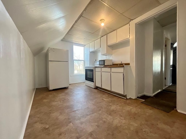 kitchen featuring baseboards, white cabinets, a drop ceiling, electric range oven, and freestanding refrigerator