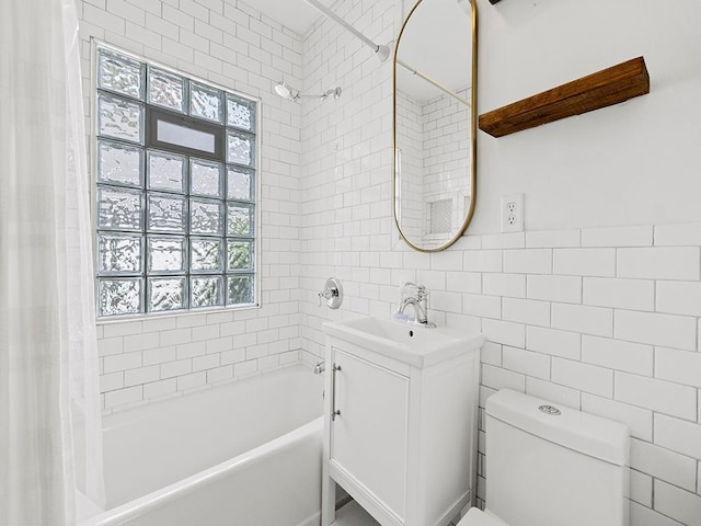 full bathroom with vanity, a healthy amount of sunlight, toilet, and tile walls