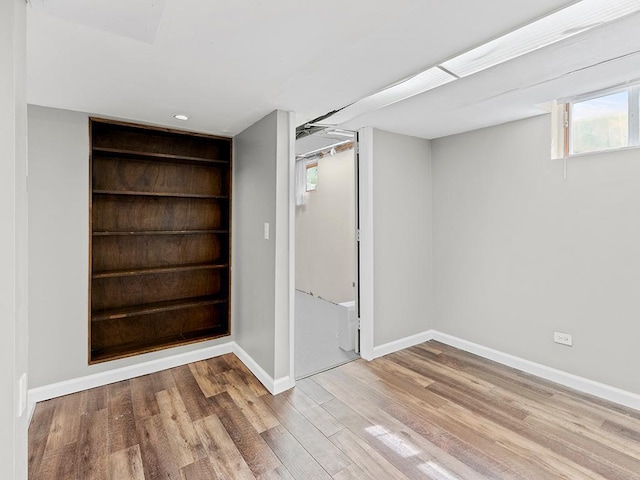 basement with built in shelves and light hardwood / wood-style flooring