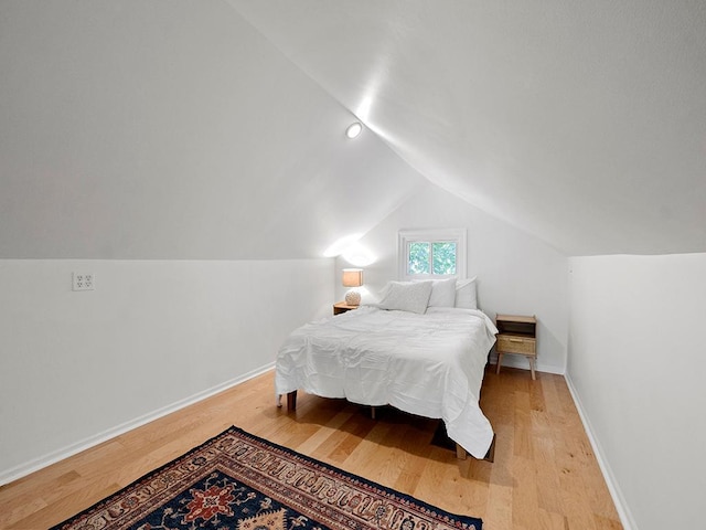 bedroom with light hardwood / wood-style floors and lofted ceiling