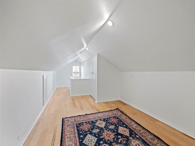 additional living space with light hardwood / wood-style flooring and lofted ceiling