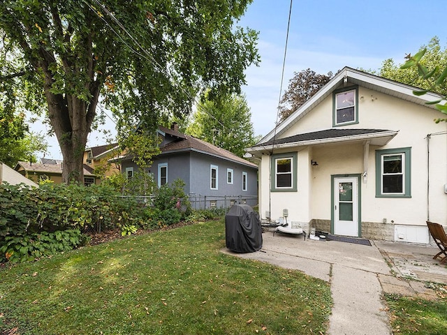 back of house with a patio and a lawn