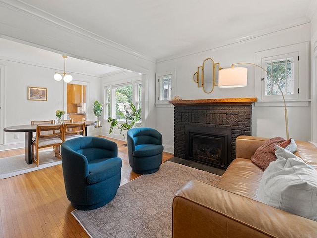 living room with hardwood / wood-style flooring, a brick fireplace, and crown molding