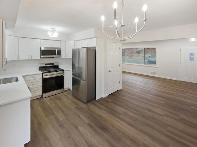 kitchen featuring dark wood-type flooring, white cabinets, stainless steel appliances, and a notable chandelier