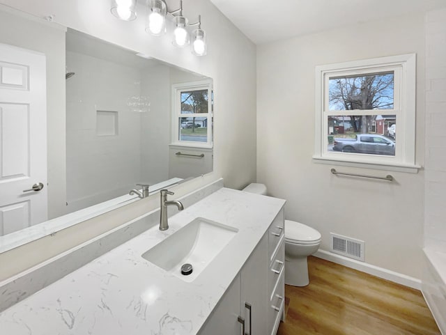 bathroom featuring a shower, vanity, hardwood / wood-style flooring, and toilet