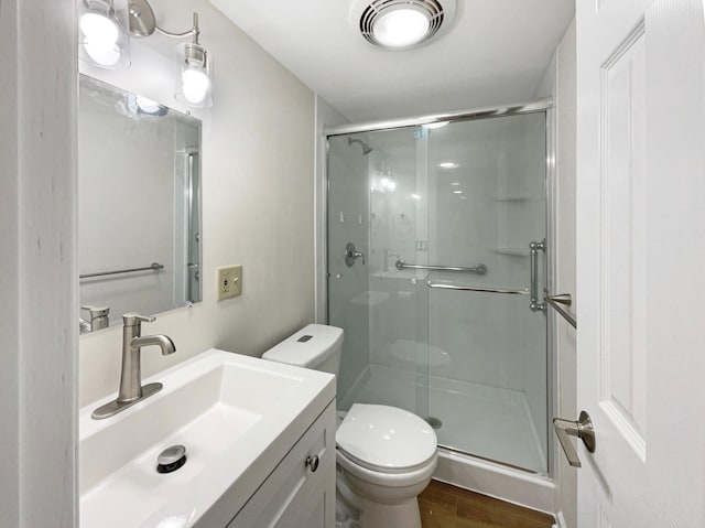 bathroom featuring hardwood / wood-style flooring, toilet, and a shower with shower door