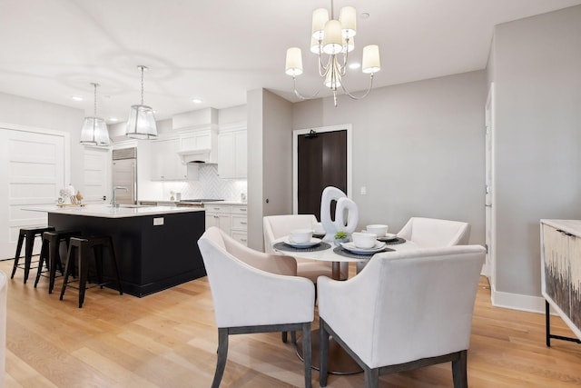 dining space with light hardwood / wood-style flooring, a notable chandelier, and sink