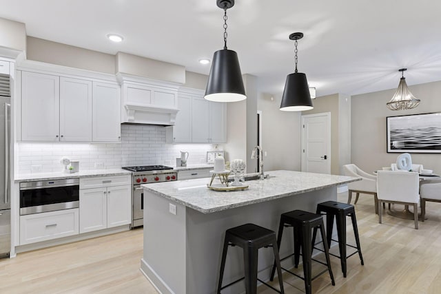 kitchen featuring light wood-style floors, backsplash, oven, and stainless steel stove