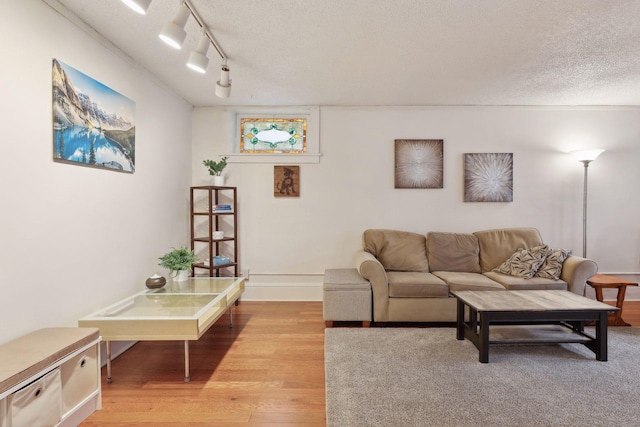 living room featuring a textured ceiling, rail lighting, and light hardwood / wood-style flooring