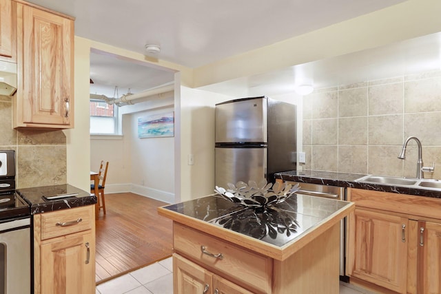 kitchen with sink, light tile patterned floors, appliances with stainless steel finishes, tasteful backsplash, and a kitchen island