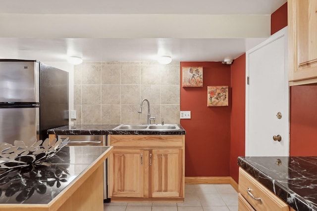 kitchen with backsplash, stainless steel fridge, sink, and light tile patterned flooring