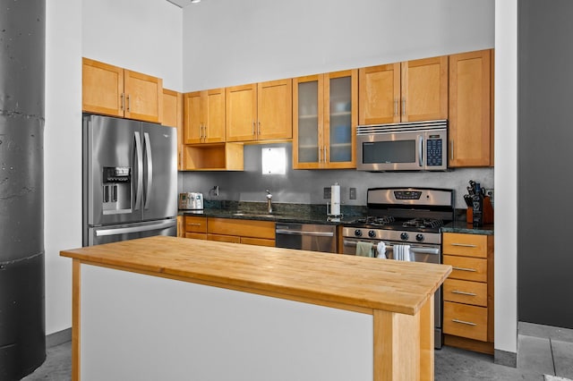 kitchen with a center island, stainless steel appliances, butcher block counters, and sink