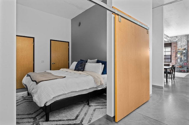 bedroom featuring concrete flooring, a barn door, and a closet