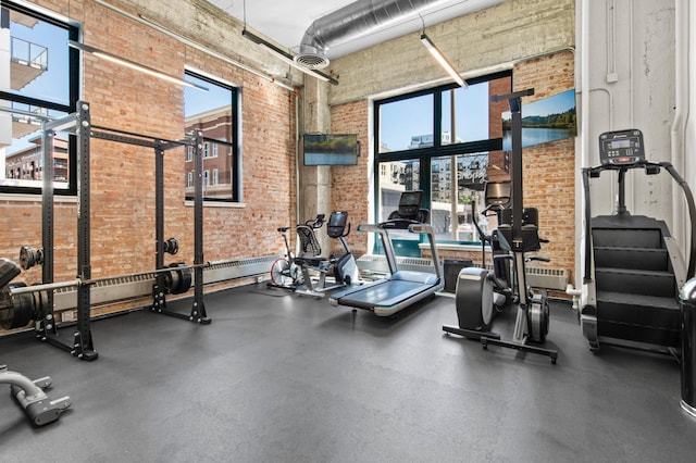 gym featuring a towering ceiling and brick wall