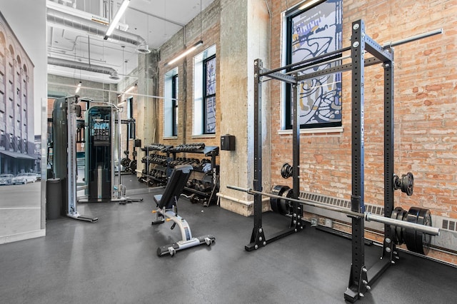 gym featuring a towering ceiling and brick wall