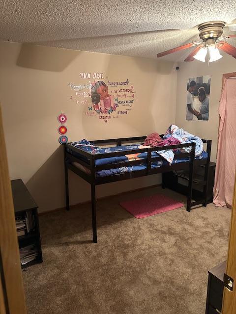 bedroom featuring ceiling fan, carpet floors, and a textured ceiling