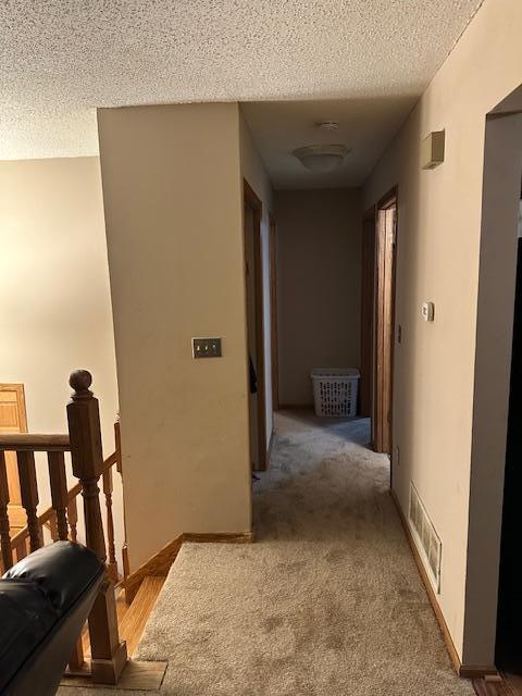 hall with carpet flooring and a textured ceiling