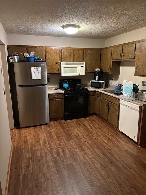 kitchen featuring a textured ceiling, dark hardwood / wood-style flooring, stainless steel appliances, and sink