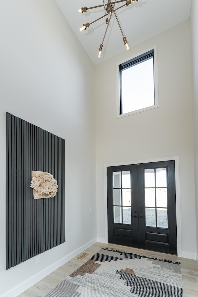 entryway featuring a high ceiling, plenty of natural light, light wood-type flooring, and french doors