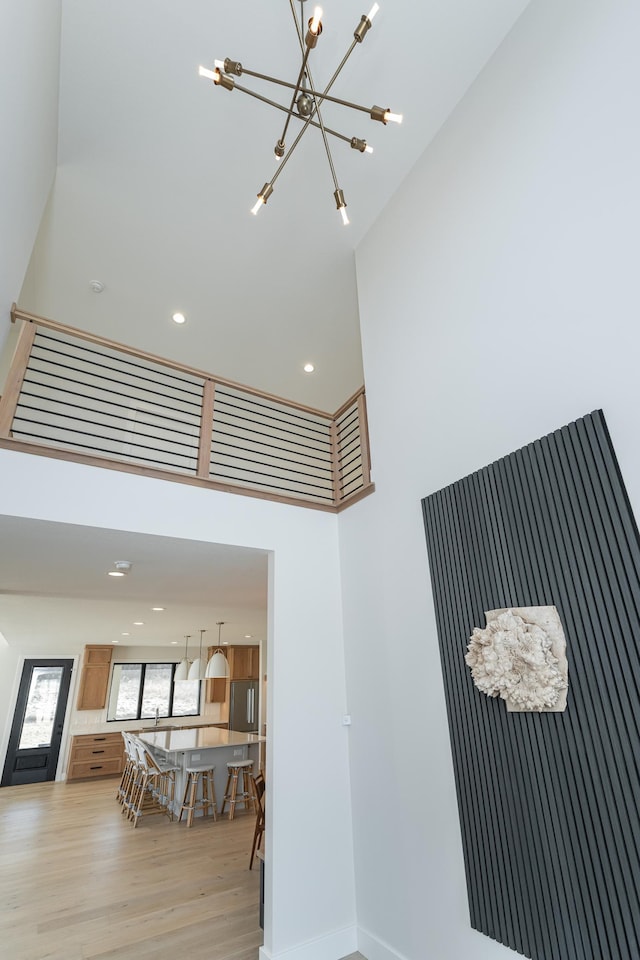 stairs featuring hardwood / wood-style flooring, a towering ceiling, and a chandelier