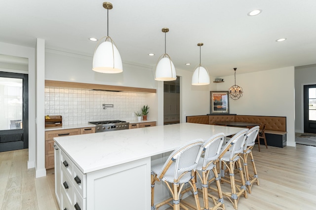 kitchen featuring hanging light fixtures, a kitchen island, white cabinets, and light stone counters