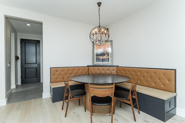 dining room with breakfast area, wood-type flooring, and an inviting chandelier