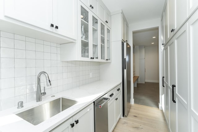 kitchen featuring stainless steel fridge, light stone countertops, sink, and white cabinets