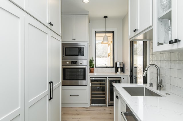 kitchen with appliances with stainless steel finishes, pendant lighting, sink, beverage cooler, and backsplash