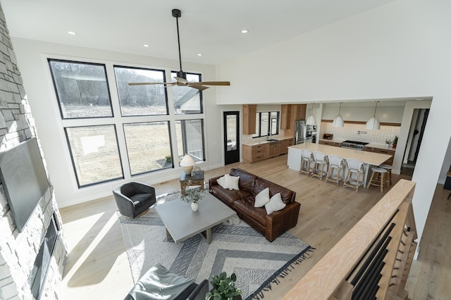 living room featuring a high ceiling, light wood-type flooring, and ceiling fan