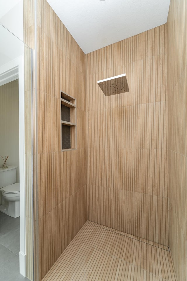 bathroom featuring tiled shower and toilet