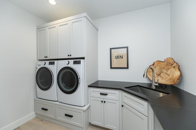 laundry room with washer and dryer, sink, light hardwood / wood-style floors, and cabinets