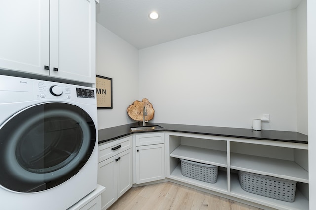 clothes washing area featuring washer / clothes dryer, cabinets, and light hardwood / wood-style floors