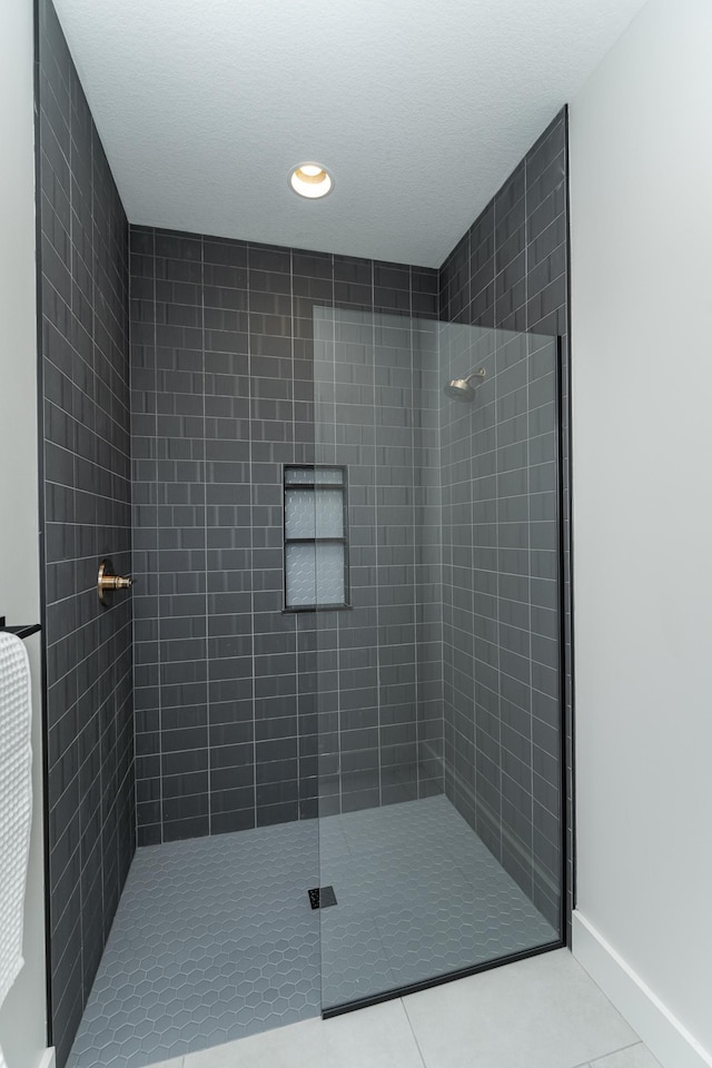 bathroom with a tile shower and tile patterned flooring